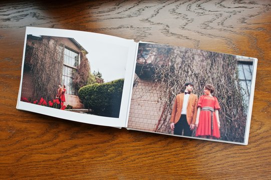 Open pages of album photobook couple in love on wooden background