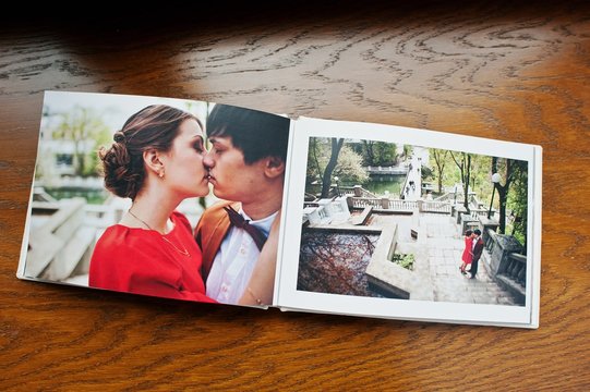Open pages of album photobook couple in love on wooden background