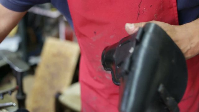 Calzolaio al Lavoro nella sua bottega artigianale. Lucidatura fondina nera di pelle. 