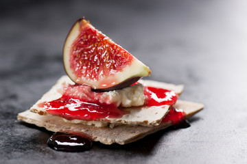 Appetizer canape with fig, jam and cheese on a small loaf of bread, closeup, selective focus