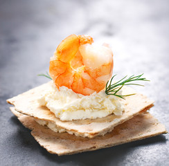 Appetizer canape with shrimp, cheese and dill on a small loaf of bread, closeup .