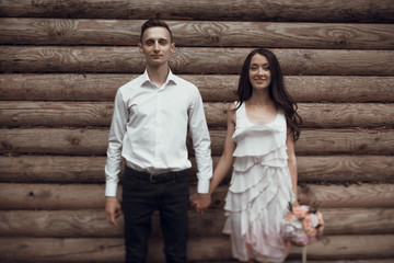 Obraz na płótnie Canvas Stylish newlyweds near the wooden wall
