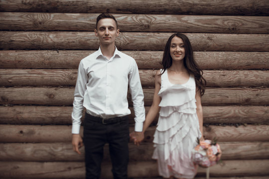 Stylish newlyweds near the wooden wall
