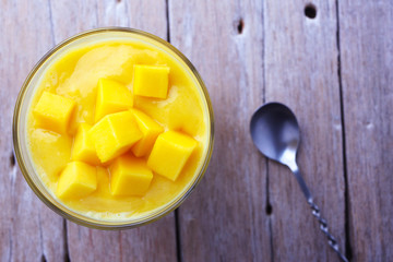 Top view of a healthy glass of mango smoothie on an old wooden table.