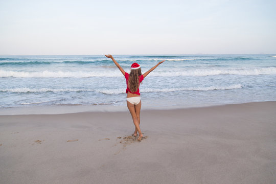 girl on the beach in Santa hat New Year traveling vacation red
