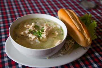 Vietnamese pho soup and a baguette in a cafe hands