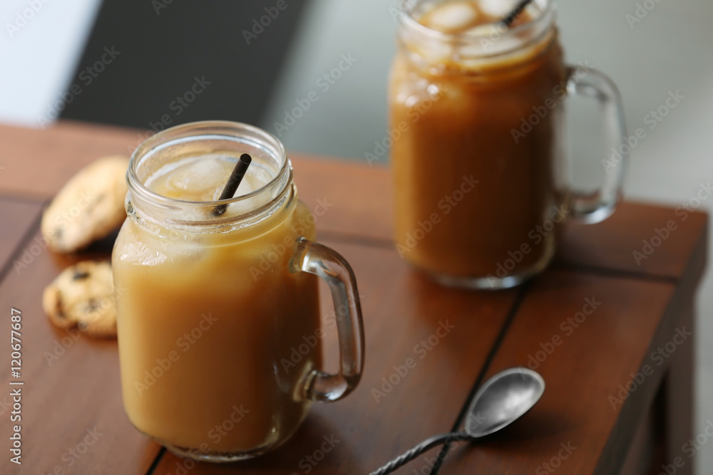 Poster iced coffee in glass jar with straw on brown wooden table