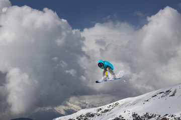 Naklejka na ściany i meble Snowboarder jumping in snowy winter mountains