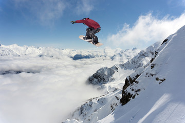 Snowboarder jumping in snowy winter mountains