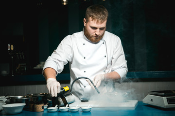 Cheerful bearded chef cook cooking while cooking meals in the kitchen