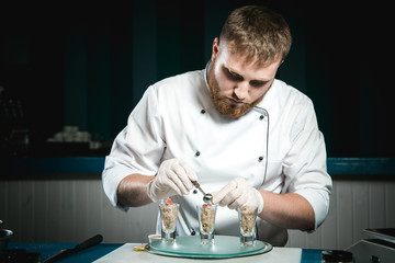Cheerful bearded chef cook cooking while cooking meals in the kitchen