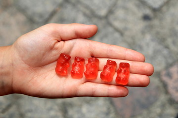 Child's hand open palmed holding five red gummi bears