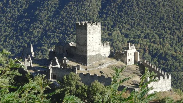 Saint-Denis, Aosta valley, Italy. View of medieval Castle ruins of Cly with mountains landscape and wood. Summer holidays, history and italian tourism destination