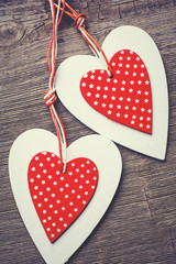 two decorative red and white heart on a wooden background.