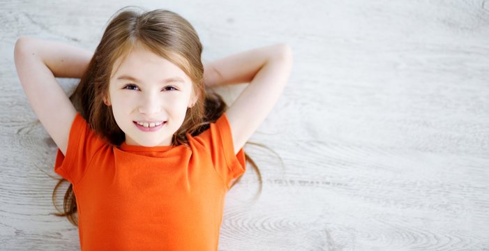 Little girl lying on white wooden floor