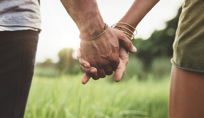 Young couple holding hands in the field - Powered by Adobe