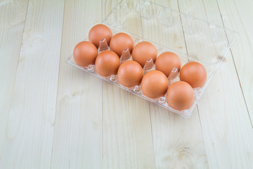 Fresh eggs in plastic tray on wooden background