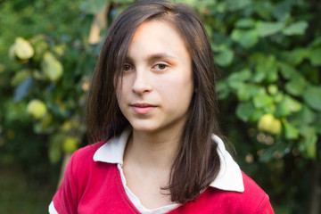 Portrait of teenage girl with dark hair near tree in orchard garden