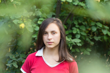 Fototapeta premium Portrait of teenage girl with dark hair near tree in orchard garden