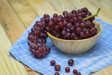 Fresh bunch of ripe red grapes in wood bolw on  blue napkin - selective focus