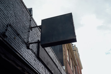 Photo blank signboard on the street. Black square signboard on the black brick wall. Mock up.