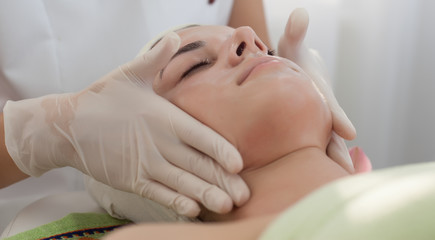 Fototapeta na wymiar Facial massage,beautician makes facial massage ,skin treatment to a beautiful young girl