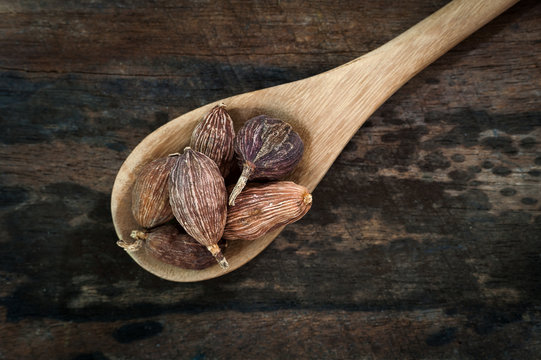 Black Cardamom (Tsaoko Fruit) on wooden spoon over wooden background