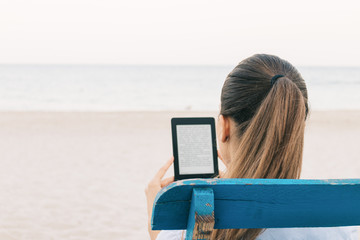 Close-up of brunette reading a book on the beach, view from the