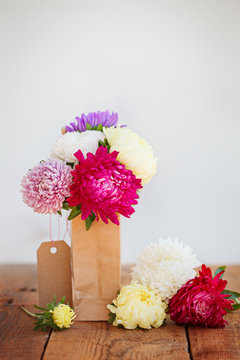 Bouquet of colorful asters in paper bag. Autumn
