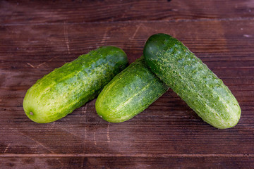 Three cucumbers on a wooden background..