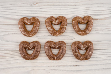 Gingerbread heart cookies on a wooden white background.