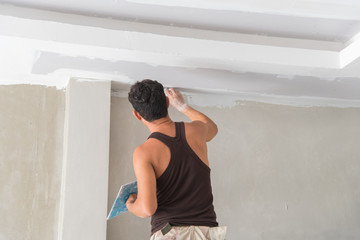 Worker working manual with wall plastering tools inside a house. Plasterer renovating indoor walls and ceilings with float and plaster,Worker painting the edges of the ceiling with Paintbrush