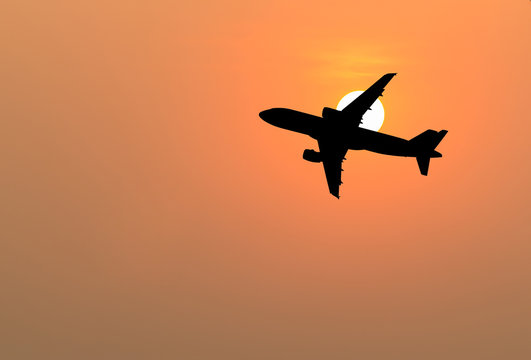 Silhouette of big airplane on beautiful orange sunset background, fast aerial transport, traveling and voyage concept