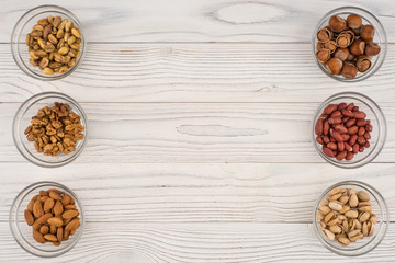 Mix nuts in a glass bowl on the old wooden table.