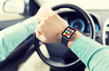 close up of man with app on smartwatch driving car