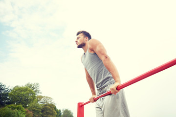 young man exercising on horizontal bar outdoors