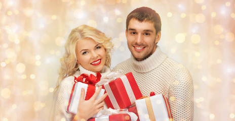 Fototapeta na wymiar happy couple in sweaters holding christmas gifts 