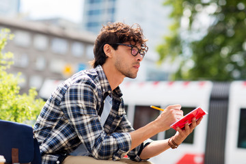 man with notebook or diary writing on city street