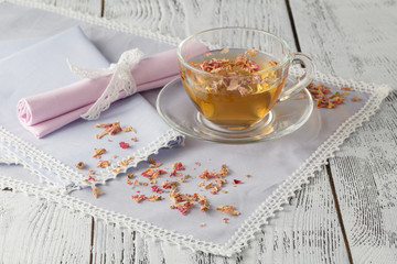 Glass cup with fresh green tea and dry roses