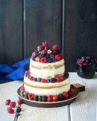 Two tiered white semi naked cake with fresh berries for a wedding or a party