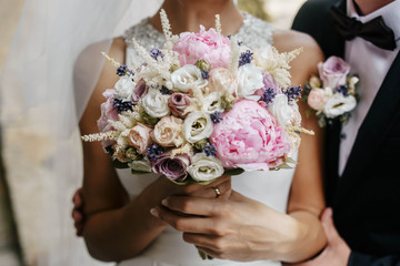 gentle bride holding a beautiful bouquet of flowers