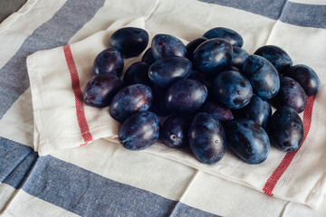 Ripe plums on textile napkins and rural tablecloth
