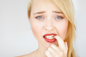 Beautiful red woman with confused look portrait. Young carroty girl with freckles feels at a loss. Thinking female pondering over something and biting her finger.