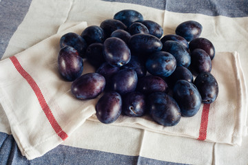 Ripe plums on textile napkins and rural tablecloth