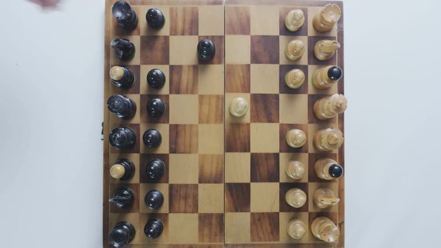 Plan view of a chess board. Beginning of the game. First moves. Static camera. White background.
