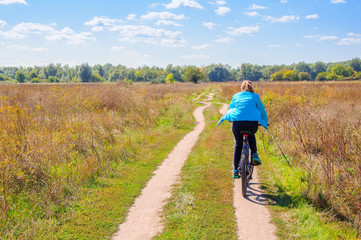 Obraz premium Girl walking with bicycle on the rural road