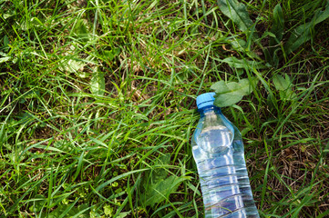 Plastic bottle with water on grass with space