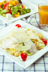 Caesar salad with chicken and greens on wooden table