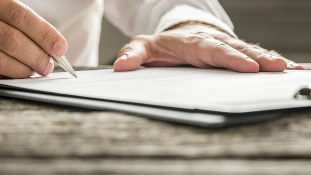 Man in white shirt signing business document
