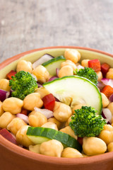 Chickpea salad in brown bowl on wooden background

